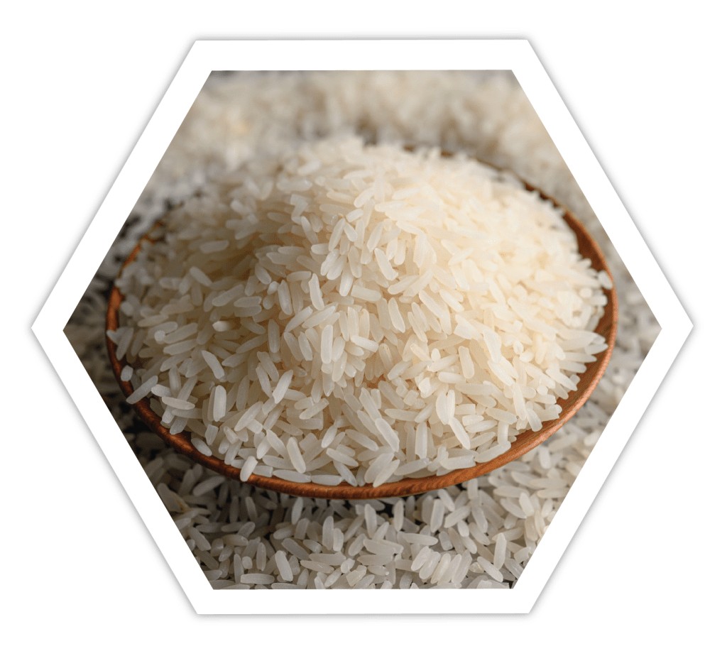 A bowl filled with uncooked white rice surrounded by scattered rice grains on a dark background.